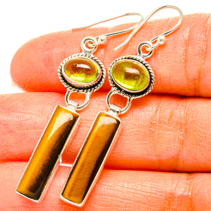 Peridot and tiger eye drop earrings close-up: round green stones with tiger-eye bars