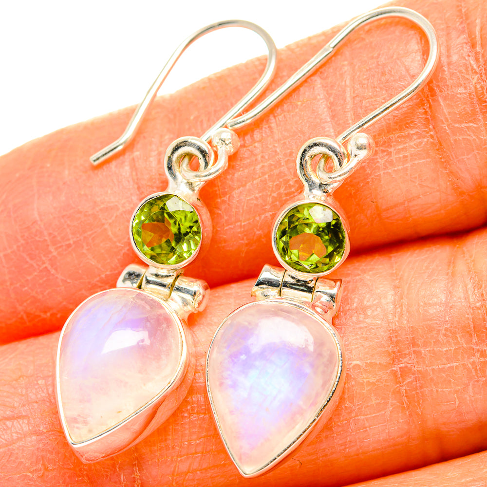 Close-up: green peridot stud and white pear-shaped moonstone dangle earrings on hooks