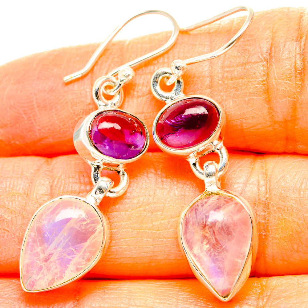 Close-up: silver drop earrings with bright pink-purple oval and pear-shaped stones on hooks