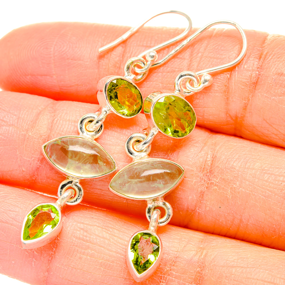 Close-up of sterling silver drop earrings with green peridot ovals and dangling charms