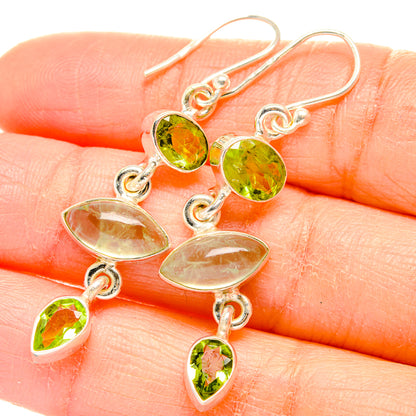 Close-up of sterling silver drop earrings with green peridot ovals and dangling charms