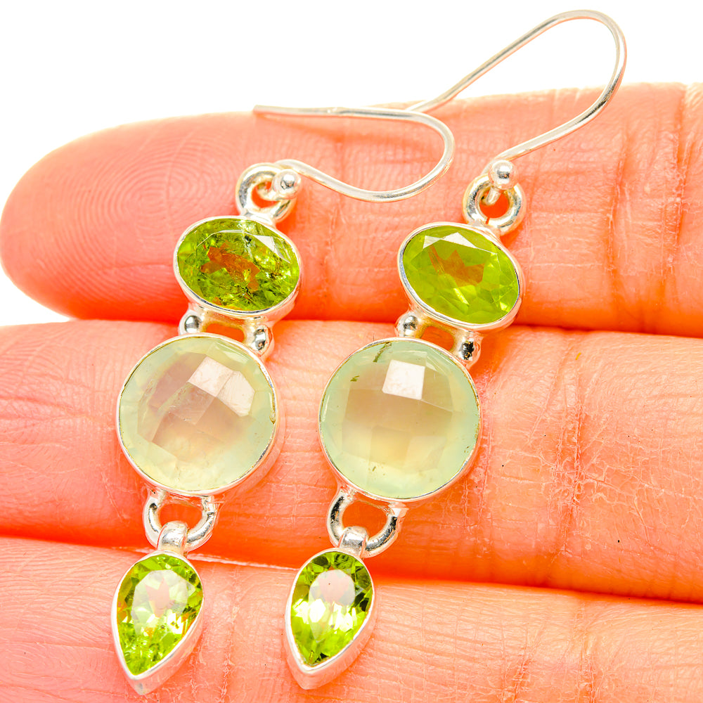 Sterling silver drop earrings with green faceted round and teardrop gemstones, close-up.