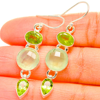 Sterling silver drop earrings with green faceted round and teardrop gemstones, close-up.