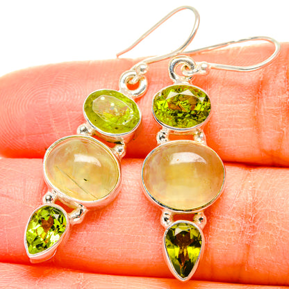 Closeup of sterling silver drop earrings with green oval and teardrop stones, pale ovals