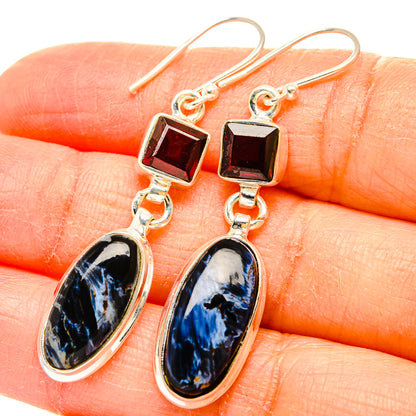 Closeup sterling silver earrings with square garnet and blue pietersite oval drops