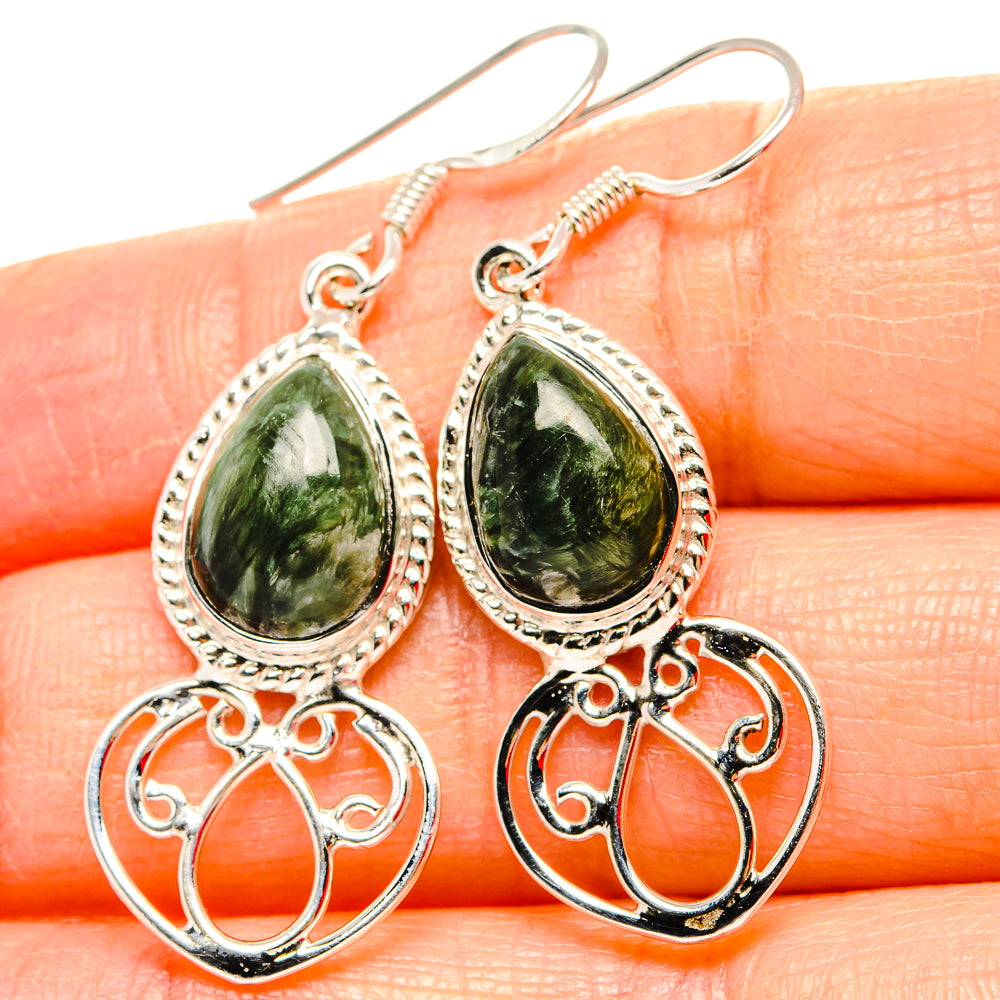 Close-up of sterling silver earrings with green teardrop gemstone and filigree drop