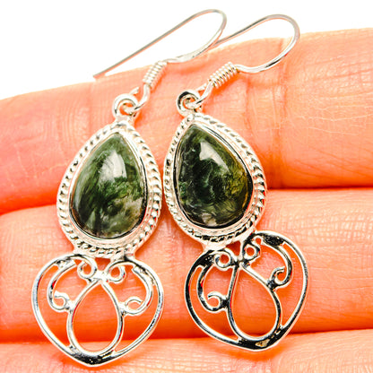 Close-up of sterling silver earrings with green teardrop gemstone and filigree drop