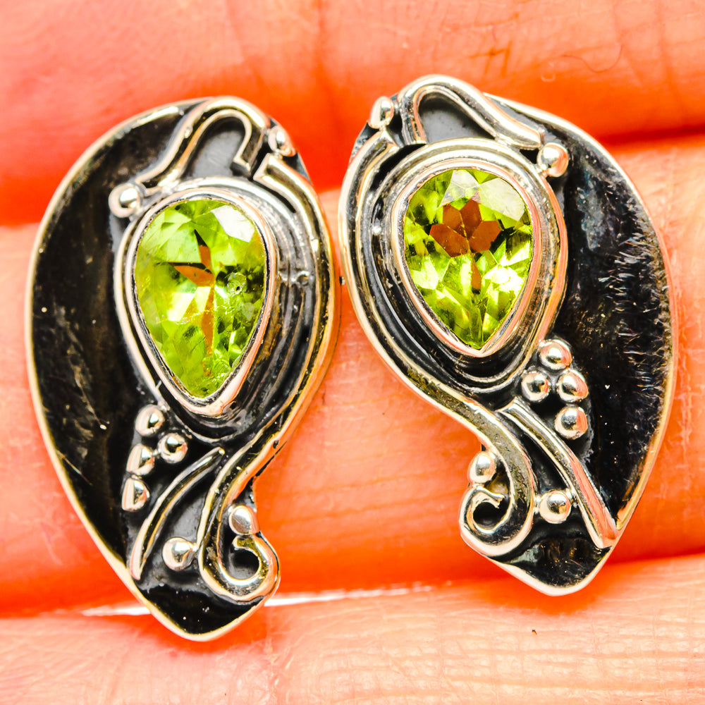 Sterling silver peridot earrings with teardrop green gemstones in ornate scroll settings