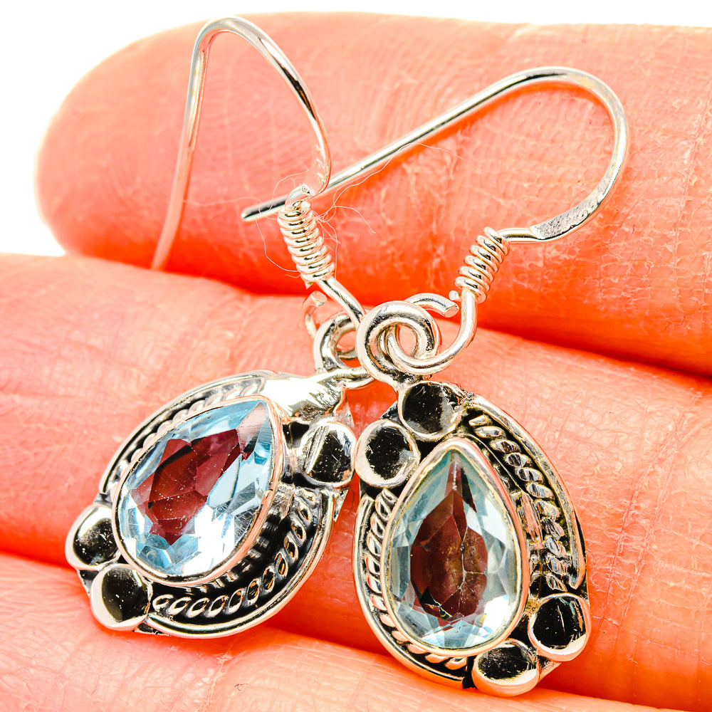 Close-up of sterling silver blue topaz drop earrings with teardrop-oval stones and loops