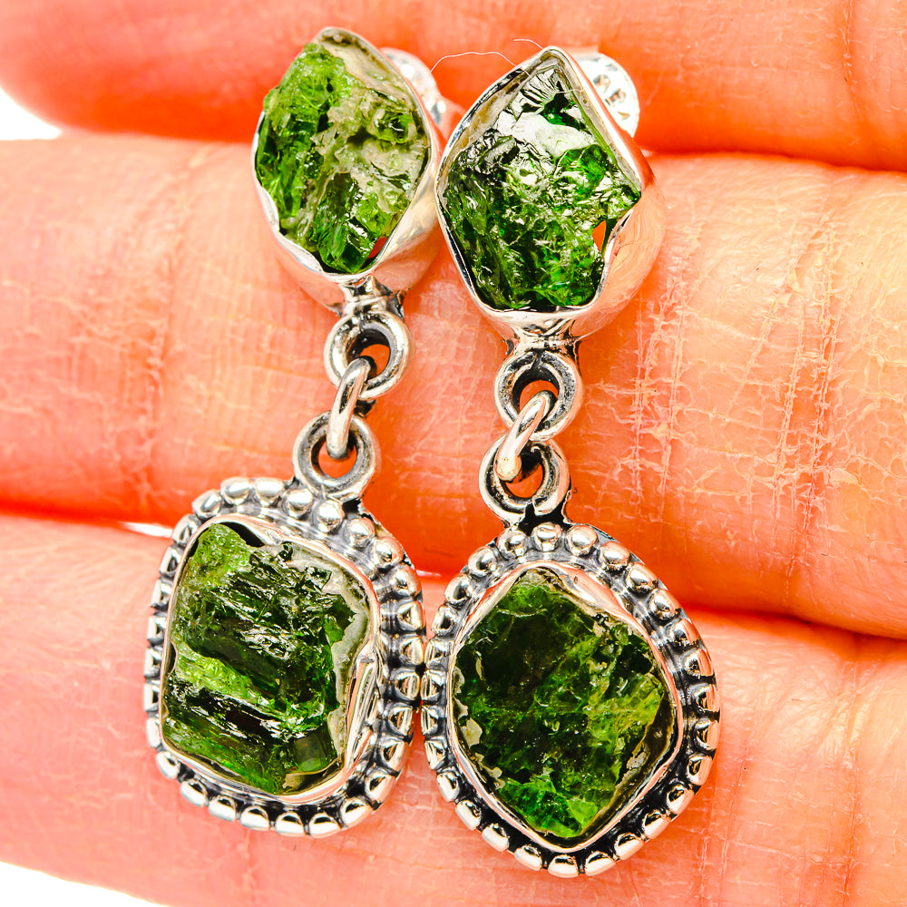 Silver-tone earrings with rough green diopside drops and dangling oval charms
