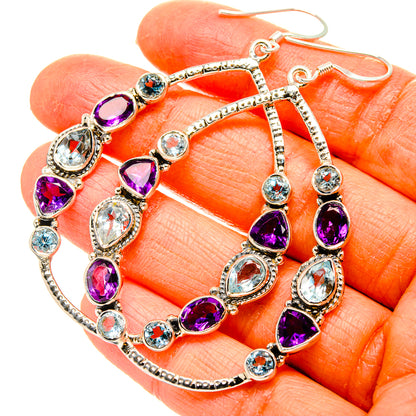 Sterling silver amethyst and blue topaz hoop-style drop earrings on fingers