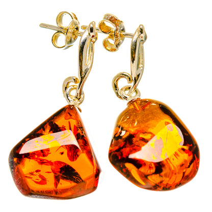 Gold-tone hoop earrings with dangling amber teardrop stones and small charm links