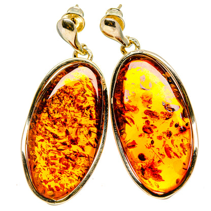Gold-tone oval hoop drop earrings with amber-colored teardrop stones and silver setting