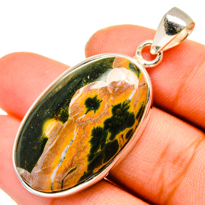 Ocean jasper cabochon pendant with 925 sterling silver bail and bezel, shown on fingertip