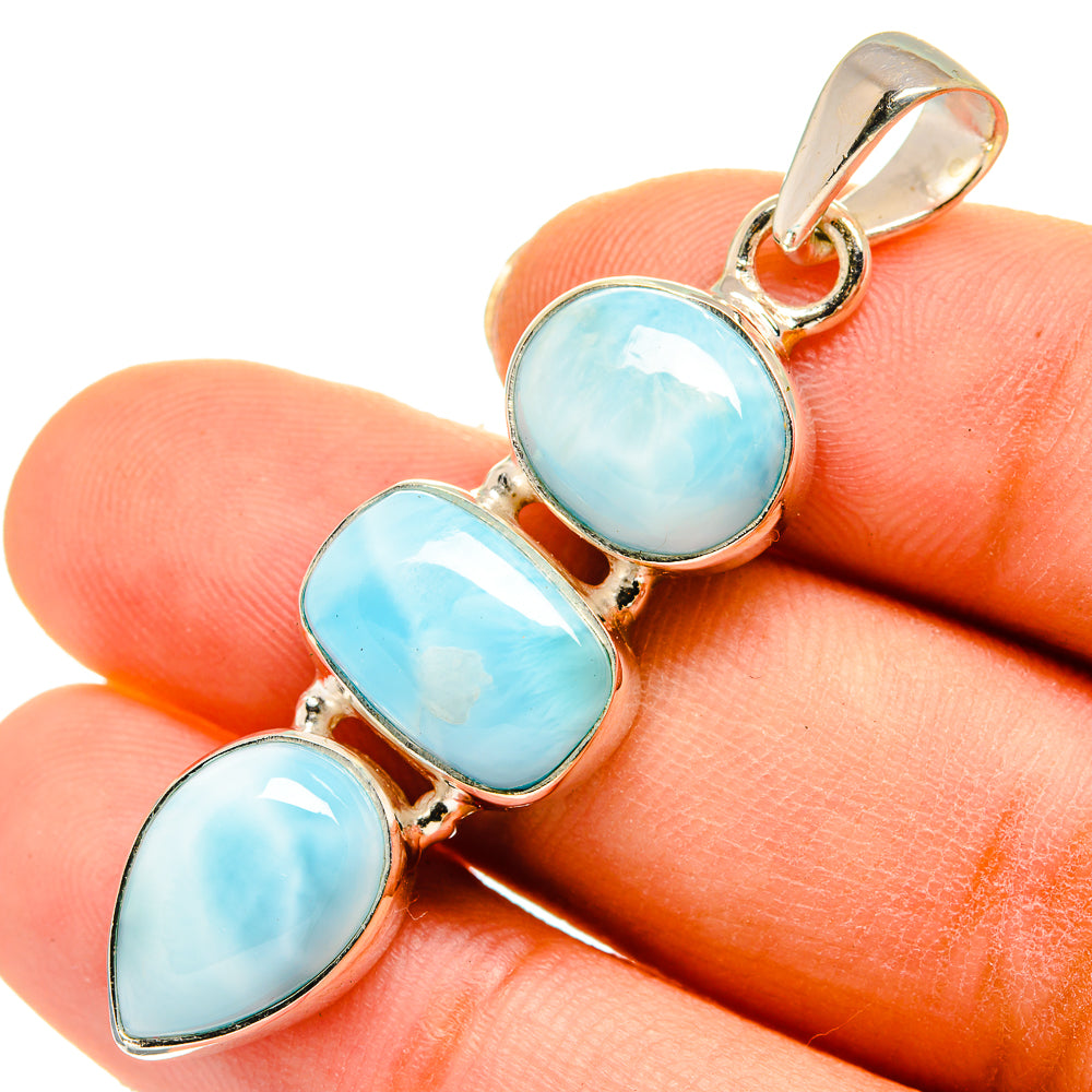 Larimar pendant close-up on hand, three oval light blue stones in silver