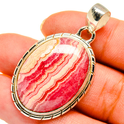 Oval rhodochrosite pendant with pink-red striped cabochon in silver bezel