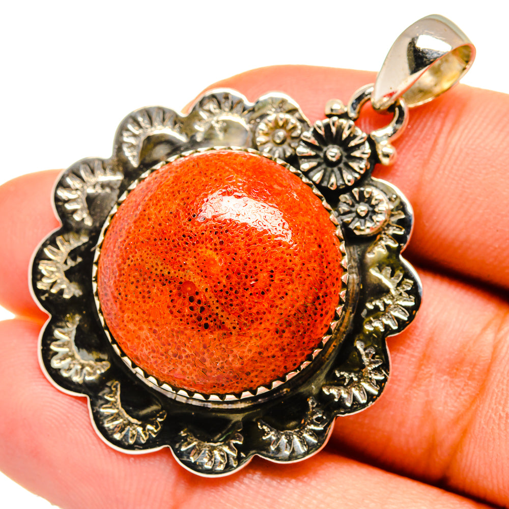 Orange coral cabochon pendant with ornate silver-toned floral frame and bail