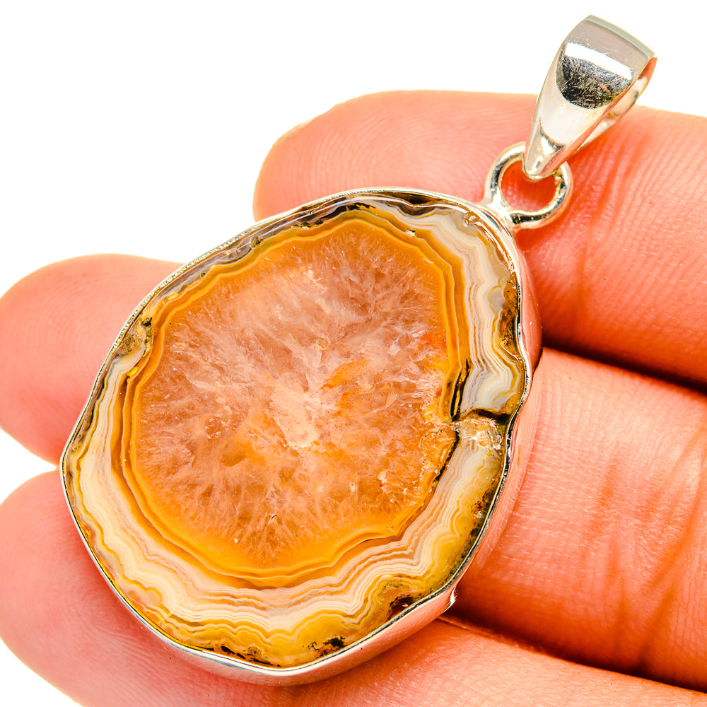 Yellow geode pendant in silver setting, orange banded geode on finger