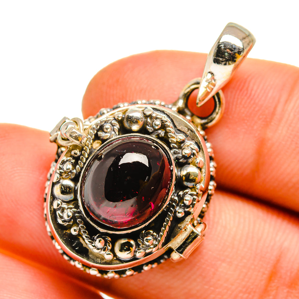 Round sterling silver pendant with dark red cabochon, detailed beaded border.