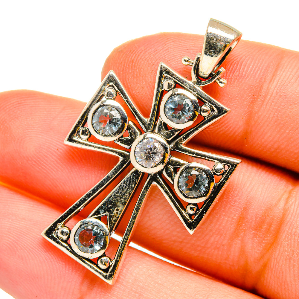Sterling silver cross pendant with blue topaz and clear round stones, close-up on bail