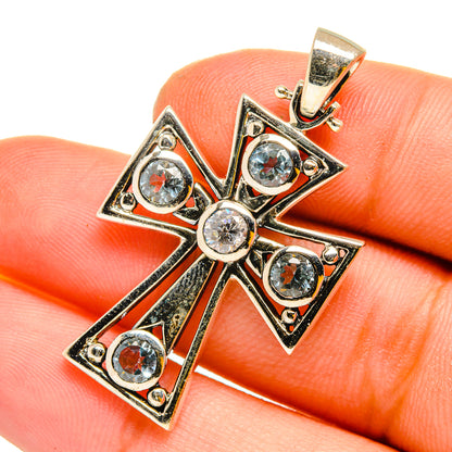 Sterling silver cross pendant with blue topaz and clear round stones, close-up on bail