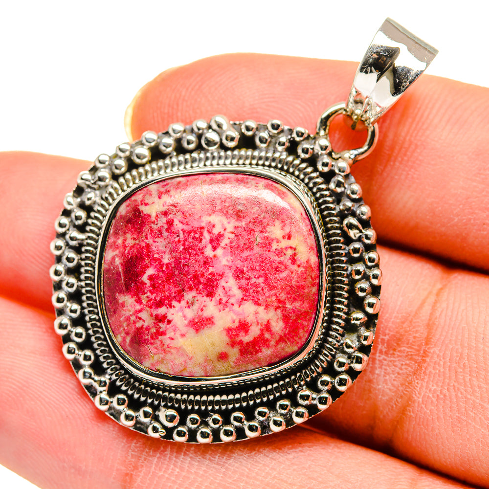 Sterling silver round gemstone pendant with red cabochon and beaded border, close-up