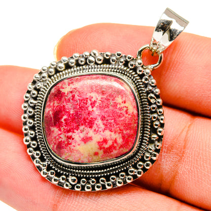 Sterling silver round gemstone pendant with red cabochon and beaded border, close-up