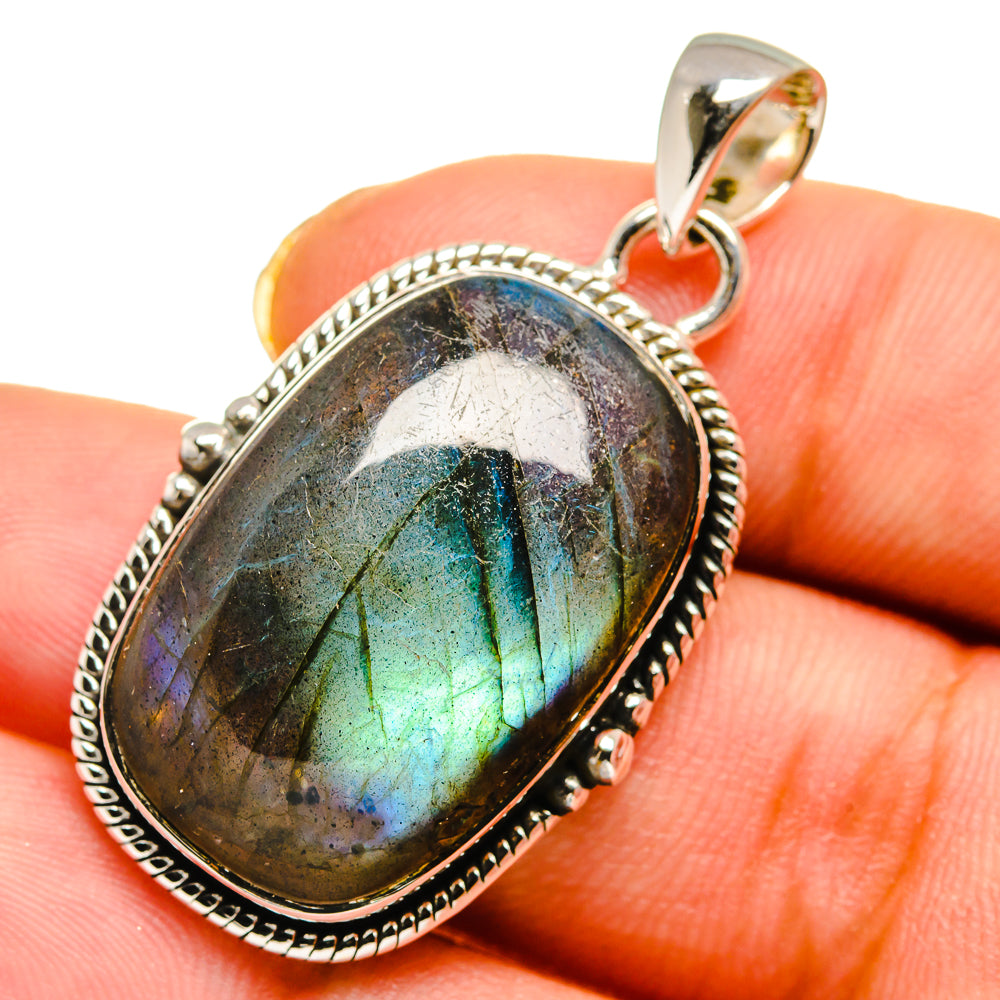 Oval labradorite pendant close-up with blue-green iridescence in silver bezel, bail loop