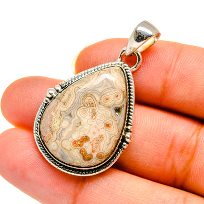 Teardrop ocean jasper pendant with sterling silver bail, held on fingertip