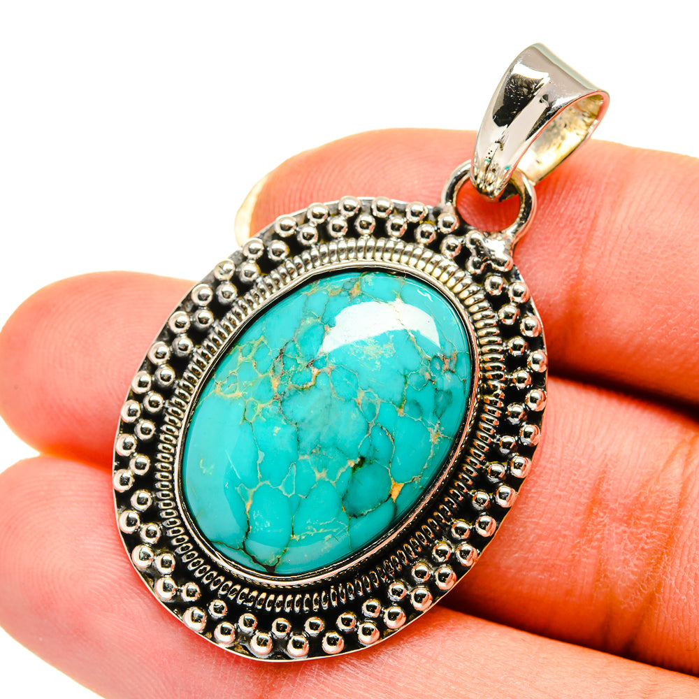 Turquoise oval pendant with ornate silver frame, bead edge, and metal bail