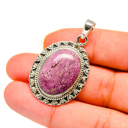 Stichtite pendant held in fingers, oval purple-pink stone in ornate 925 silver frame
