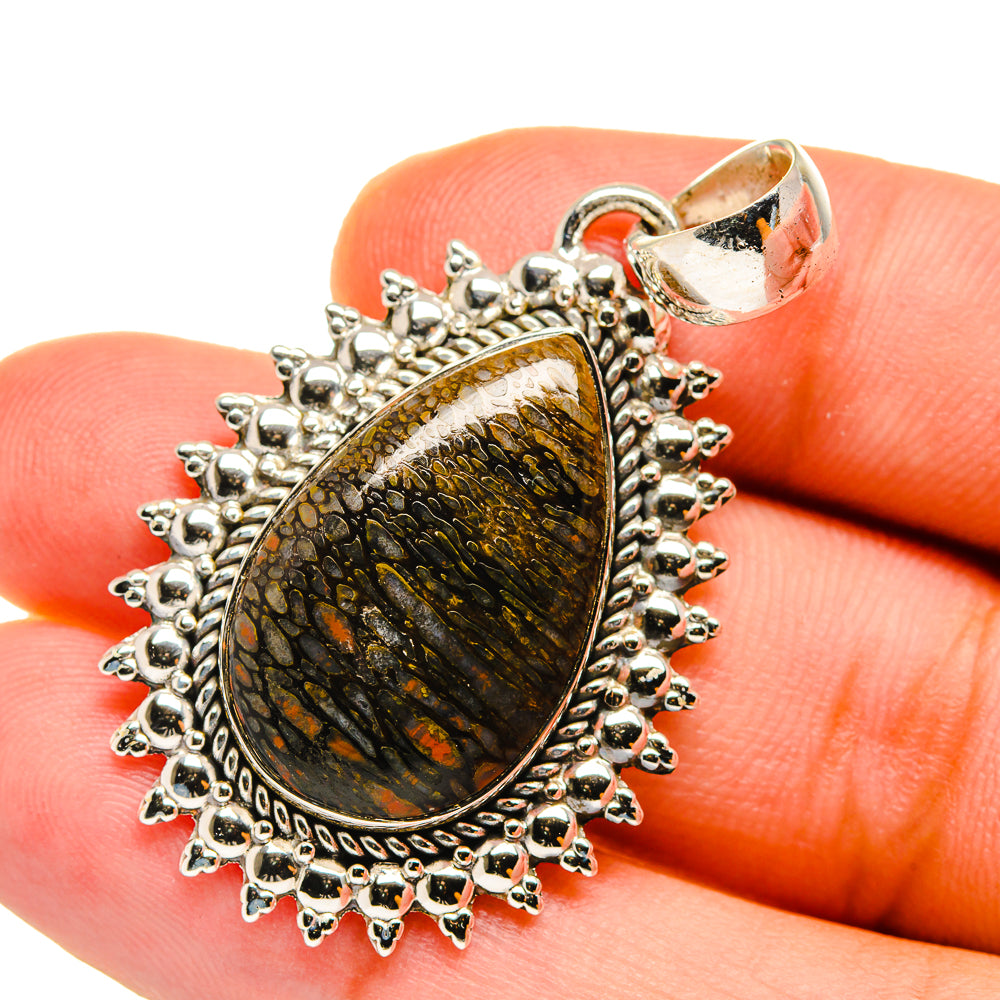 Sterling silver teardrop pendant close-up with fossil-like stone, prong border and loop bail