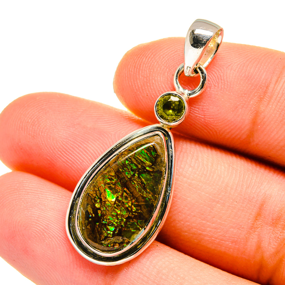 Teardrop ammolite and round green peridot pendant in silver, close-up on stones