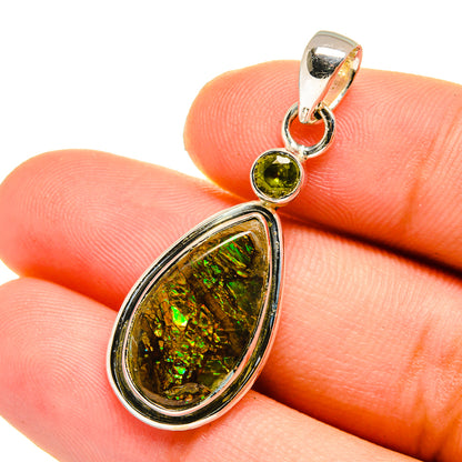 Teardrop ammolite and round green peridot pendant in silver, close-up on stones