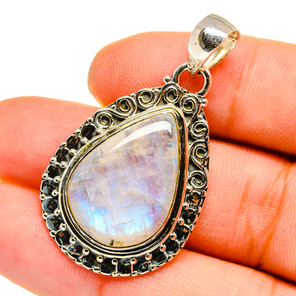 Teardrop moonstone pendant in silver with ornate border and orange accent at the bail