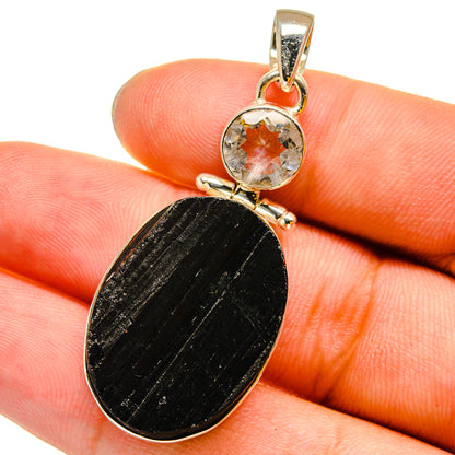 Gold-tone pendant on finger: black oval stone with round clear quartz bezel