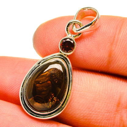 Silver pendant with oval amber stone, small round red gem, and orange accents