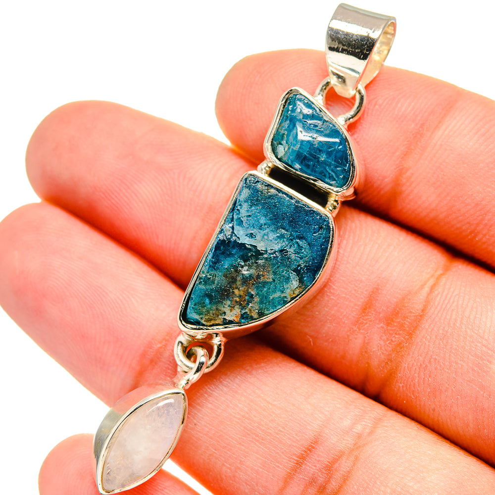 Silver pendant on hand: blue rough cabochon and pale oval opalescent stone, bail top