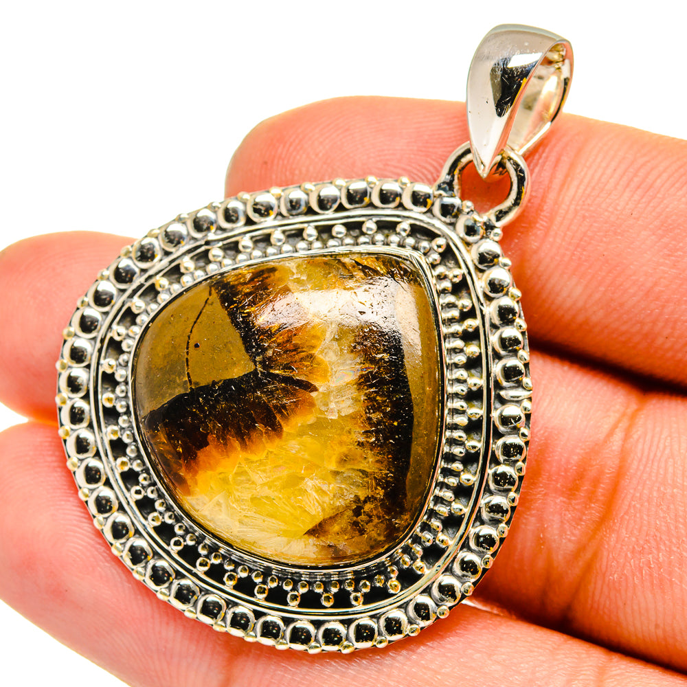 Septarian pendant close-up: oval amber stone in detailed sterling silver bezel with bail.
