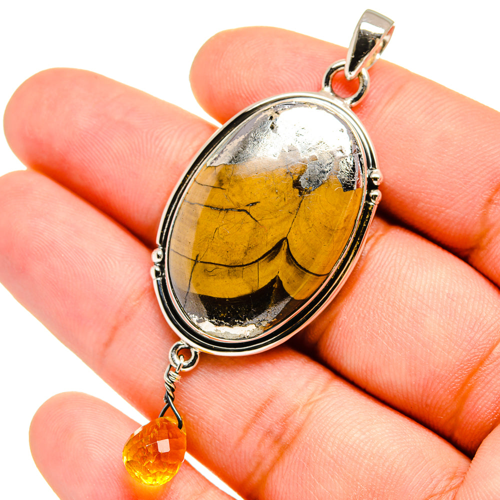 Citrine oval pendant close-up with silver bezel and dangling teardrop charm