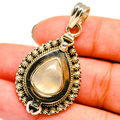 Teardrop moonstone pendant with gold-tone beaded silver frame and bail, held in hand