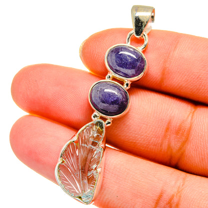 Gold-tone sterling silver pendant closeup with two blue-purple round stones and leaf