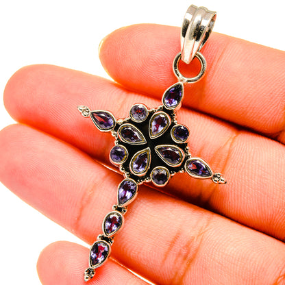 Sterling silver cross pendant with faceted purple gemstones, close-up on bail