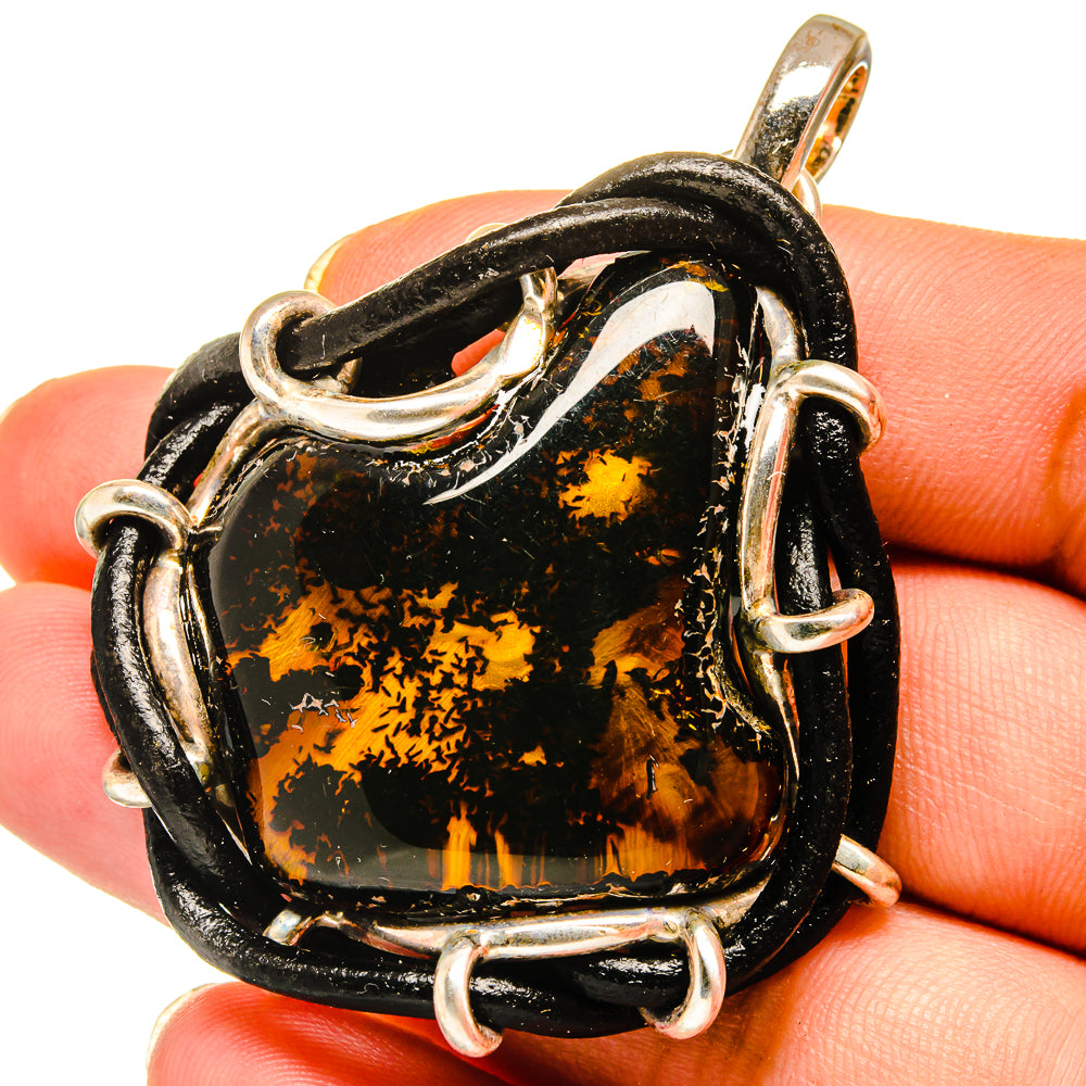 Amber pendant with black and gold stone, sterling silver prong frame and loops