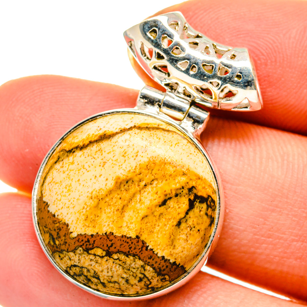 Round picture jasper pendant with silver bezel and ornate bail; yellow-brown stone.