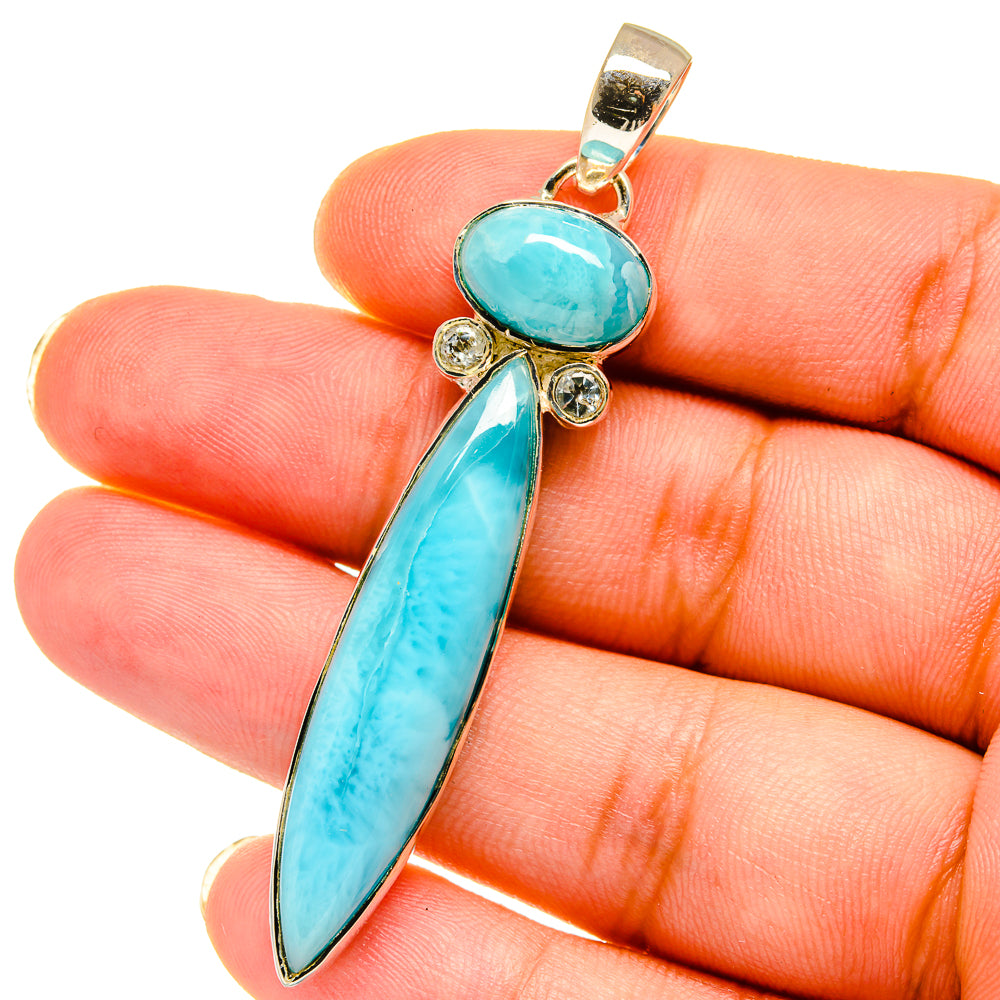Turquoise gemstone pendant held in hand; oval and elongated drop stones, gold-tone setting.