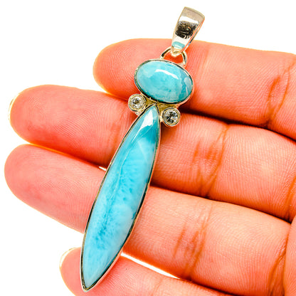 Turquoise gemstone pendant held in hand; oval and elongated drop stones, gold-tone setting.