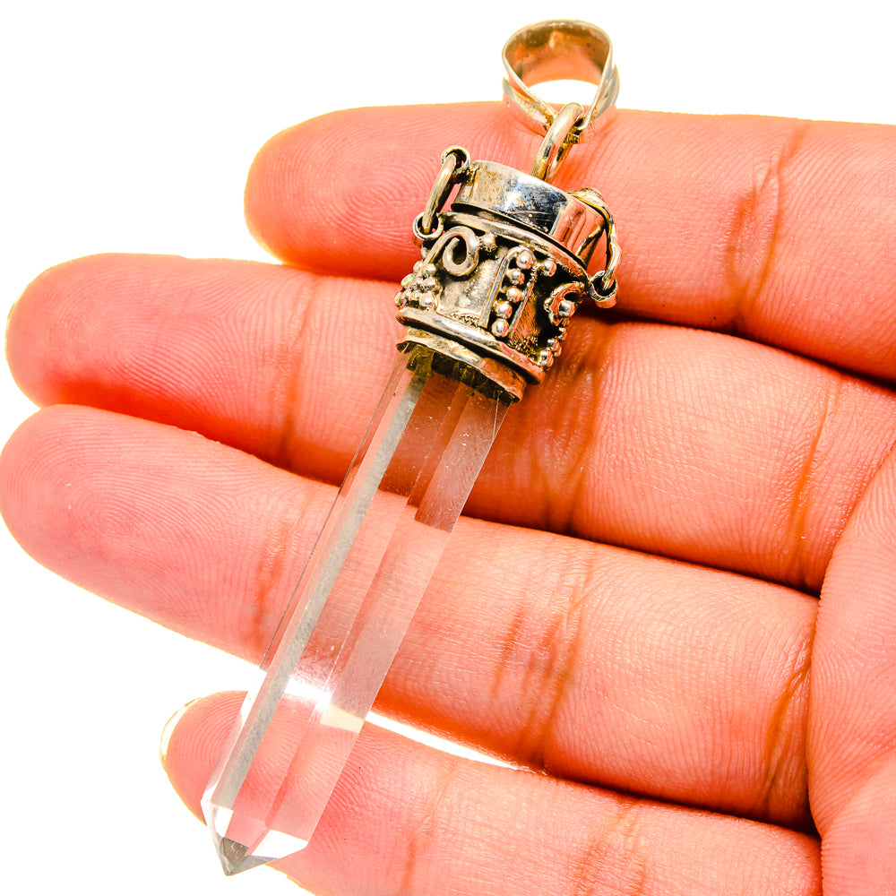 Quartz crystal pendant in silver-tone setting with gold bail, white stone tip