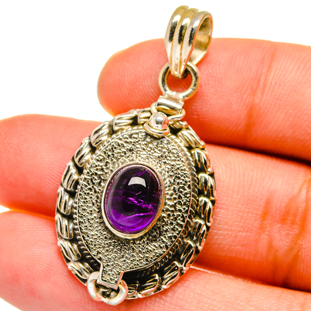 Amethyst pendant with oval textured silver setting and purple cabochon, hinged bail loop.