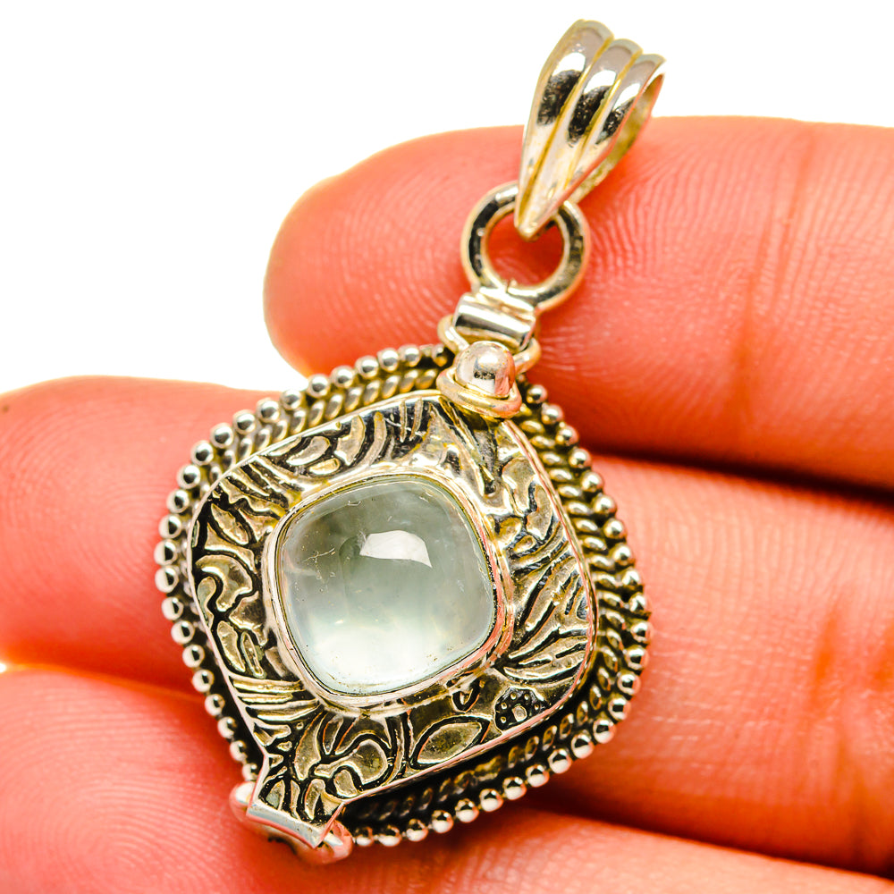 Oval aquamarine cabochon pendant with engraved frame, beaded rim, and loop bail